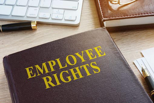 A book on an office desk titled "Employee Rights"