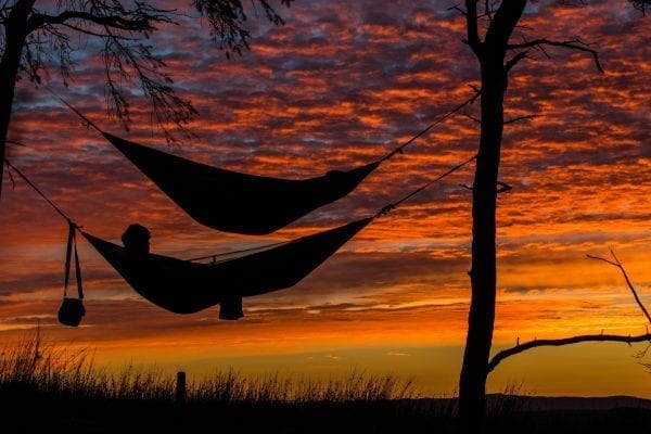 A silhouette of 2 people in hammocks