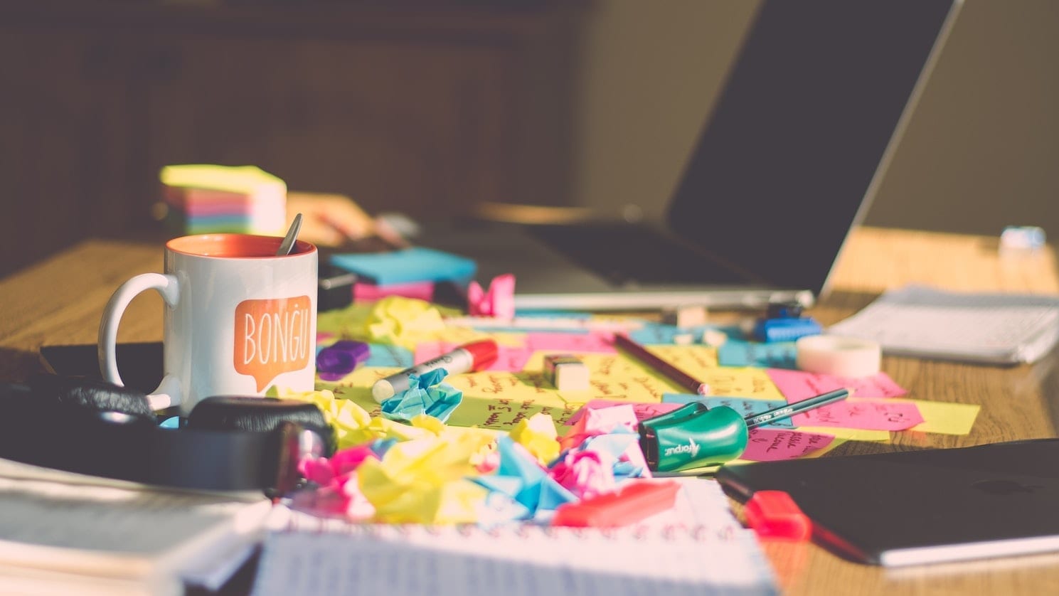 A messy meeting table with a laptop and many post-it notes on it